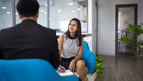 Portrait of smiling hr manager having interview with candidate. Young Caucasian businesswoman having meeting with businessman in lobby and writing after him. Meeting and job interview concept
